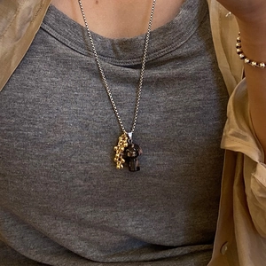 Detail of a titanium steel necklace with natural stone mushroom and gold bead charms