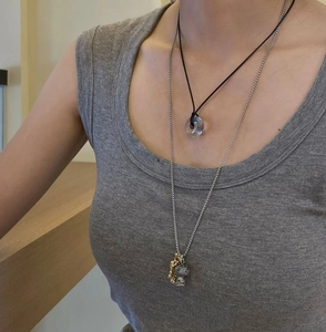 Detail of layered titanium necklace with transparent ring, bear pendant, and natural stone