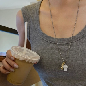 Detail of titanium steel necklace with white crystal mushroom and gold beads on model
