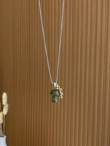 Close-up of green stone mushroom pendant with gold beads on silver steel chain
