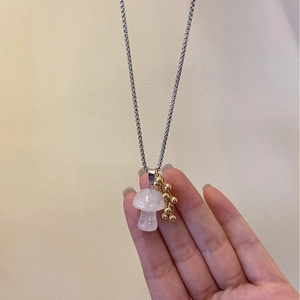 Detail shot of a pink quartz mushroom pendant with golden bead clusters on a steel chain