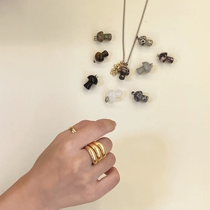 Detail view of colorful mushroom stone pendants and gold rings on beige background
