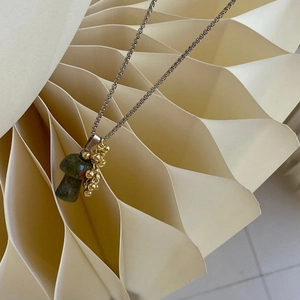 Detail of creative mushroom pendant with green stone and golden beads on box chain