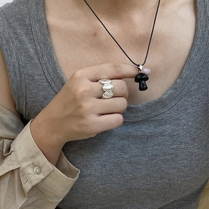 Dettaglio di una collana con pendente a fungo nero e anello d'argento indossati da una modella