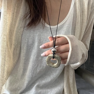 Dettaglio di una collana con pendente in osso di cammello naturale e perla d'argento