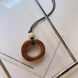 Dettaglio della collana con ciondolo in osso di cammello marrone con trama naturale