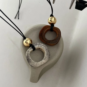 Dettaglio di ciondoli vintage in osso di cammello con trama marmorea e perle dorate
