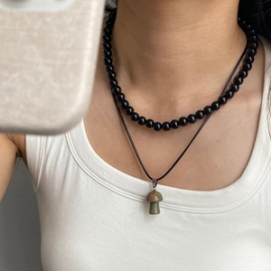 Dettaglio di una collana a strati con perline nere e ciondolo a forma di fungo in pietra