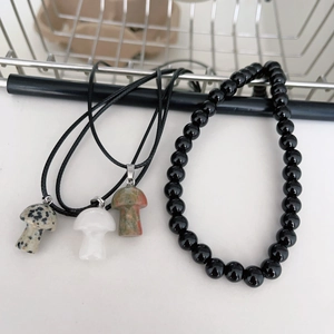 Dettaglio dei ciondoli a fungo in pietra naturale con collana di perle nere a strati