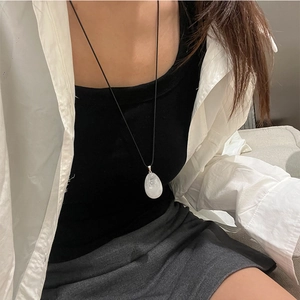 White teardrop natural stone pendant necklace on model with minimalist black cord