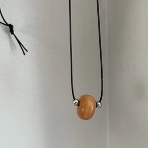 Détail du collier en cordon de cire minimaliste avec perle d'ambre et accents en acier