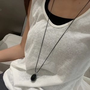 Close-up of black teardrop stone pendant worn as a long minimalist necklace