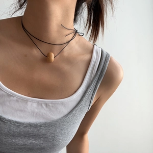 Gros plan d'un collier minimaliste à double cordon noir avec perle en ivoire végétal