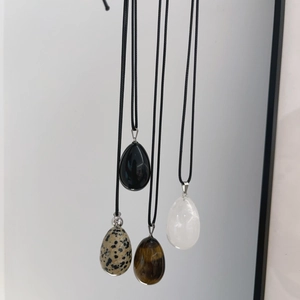 Detailed close-up of four assorted natural stone water-drop pendants on black woven cords