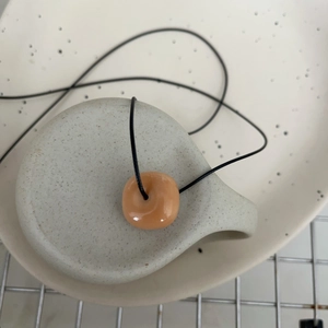 Gros plan du collier avec pendentif en forme de donut sur un support en céramique