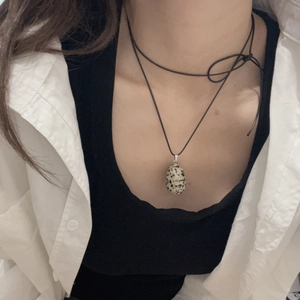Macro detail of egg-shaped spotted natural stone pendant on a black cord necklace