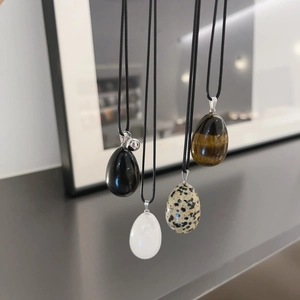 Detailed view of four oval natural stone pendants with black cords in a modern setting