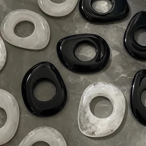 Vue détaillée d'anneaux géométriques en résine polie, noir et texture marbre