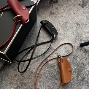 Detail of minimalist leather neck pouch set in burgundy, black and brown with fine stitching
