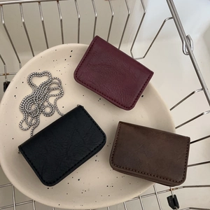 Chic leather mini chain pouches in burgundy, black, and brown displayed on ceramic plate