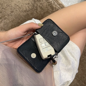 Macro shot of black pebbled leather mini bag with silver magnetic snap and chain link strap
