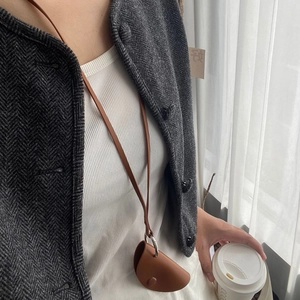 Close-up of brown leather neck pouch with metal button and long adjustable strap