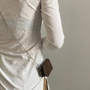 Detailed side view of a brown mini leather chain bag worn on a minimalist model
