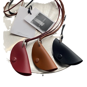 Three leather key case necklaces in burgundy, brown and black on a metal tray