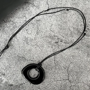 Gros plan détaillé d'un collier à pendentif rond vitré noir avec accents de perles