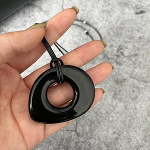 Gros plan d'un pendentif rond noir brillant en obsidienne avec cordon noir fin