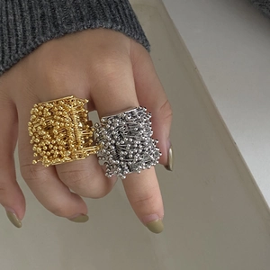 Detail shot of large cluster rings in gold and silver with industrial seed-like metallic beads