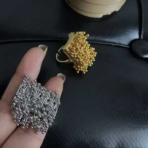 Macro shot of firework-style seed rings in gold and silver finish with textured details