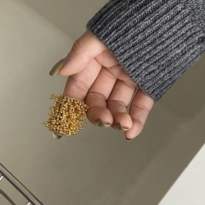 Close-up of a designer golden firework seed cluster open ring worn on a model's finger