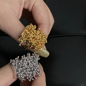 Close-up of gold and silver cluster bead firework rings on a textured black leather background