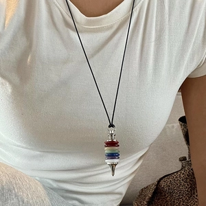 Seven chakra natural stone pendulum necklace worn by model on black cord strap