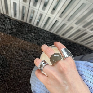 Detail of three mixed style resin and plated copper rings worn by hand holding a drink
