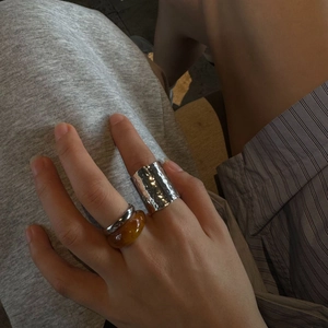 Detail of chunky silver hammered ring and amber resin band stacked on fingers