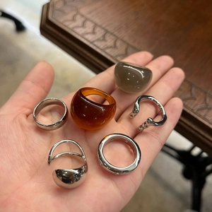 Close-up of five-piece ring set including silver metal bands and thick resin rings on palm