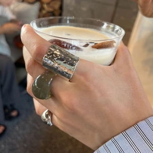 Close-up of minimalist resin and textured silver rings set worn with a coffee cup