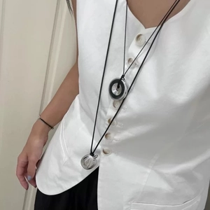 Detailed view of long minimalist necklace with silver polished orb and ring pendants