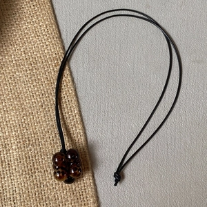 Minimalist long black cord sweater necklace featuring tiger eye bead cluster pendant