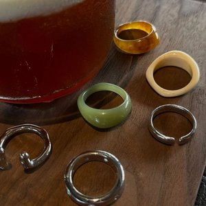 Close-up of minimalist resin and silver rings set on dark wooden surface background