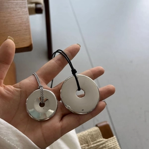 Close-up of minimalist solid metal water bottle pendant and peace buckle long necklace