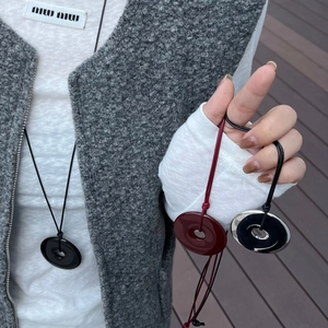 Detailed view of large resin circle pendants in black and burgundy on long cords