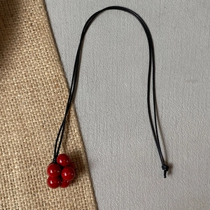 Minimalist long black cord necklace featuring a vibrant red berry-shaped beaded pendant