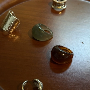 Detail shot of chunky resin and hammered metal rings on a dark wooden display tray