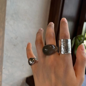 Close-up of irregular resin ring and hammered silver metal rings on a hand