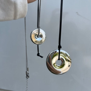 Close-up of polished silver donut pendants with black leather cord and metal chains