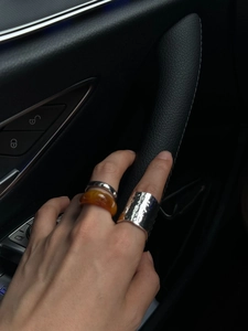 Close-up of a three-piece ring set with amber resin and hammered silver plating on a model