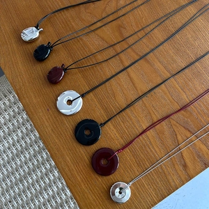 Detail of minimalist pendant necklaces showing silver and resin finish on wood